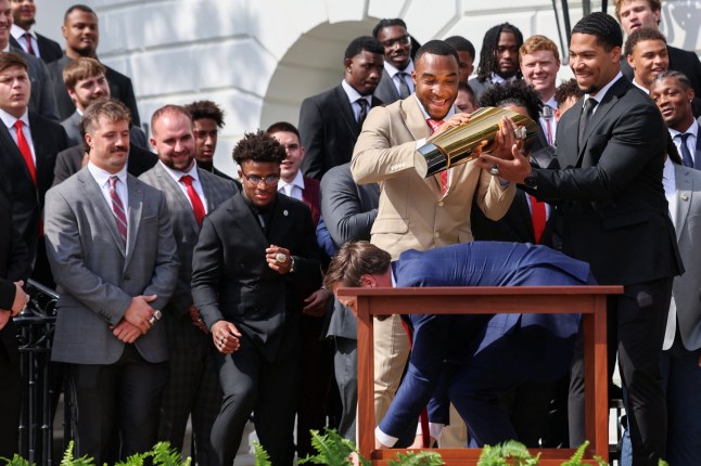 U.S. Vice President JD Vance goes to pick up part of the trophy after dropping it, as running back TreVeyon Henderson holds the other part, while Vice President Vance and President Donald Trump (not pictured) meet the Ohio State University 2025 College Football National Champions, at the White House, in Washington, D.C., U.S., April 14, 2025. REUTERS/Evelyn Hockstein