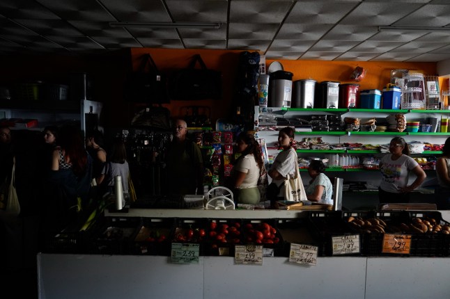 LISBON, PORTUGAL - APRIL 28: People wait in line to shop for groceries in a dark shop during a widespread power outage that struck Spain and Portugal around midday on Monday, with the cause still unknown in Lisbon, Portugal on April 28, 2025. (Photo by Stringer/Anadolu via Getty Images)