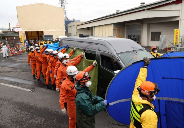Firefighters guard a vehicle carrying the body believed to be that of a male truck driver, found in a sewage pipe near the site of a road collapse that occurred on January 28, in Yashio City, Saitama Prefecture on May 2, 2025. (Photo by JIJI Press / AFP) / Japan OUT (Photo by STR/JIJI Press/AFP via Getty Images)